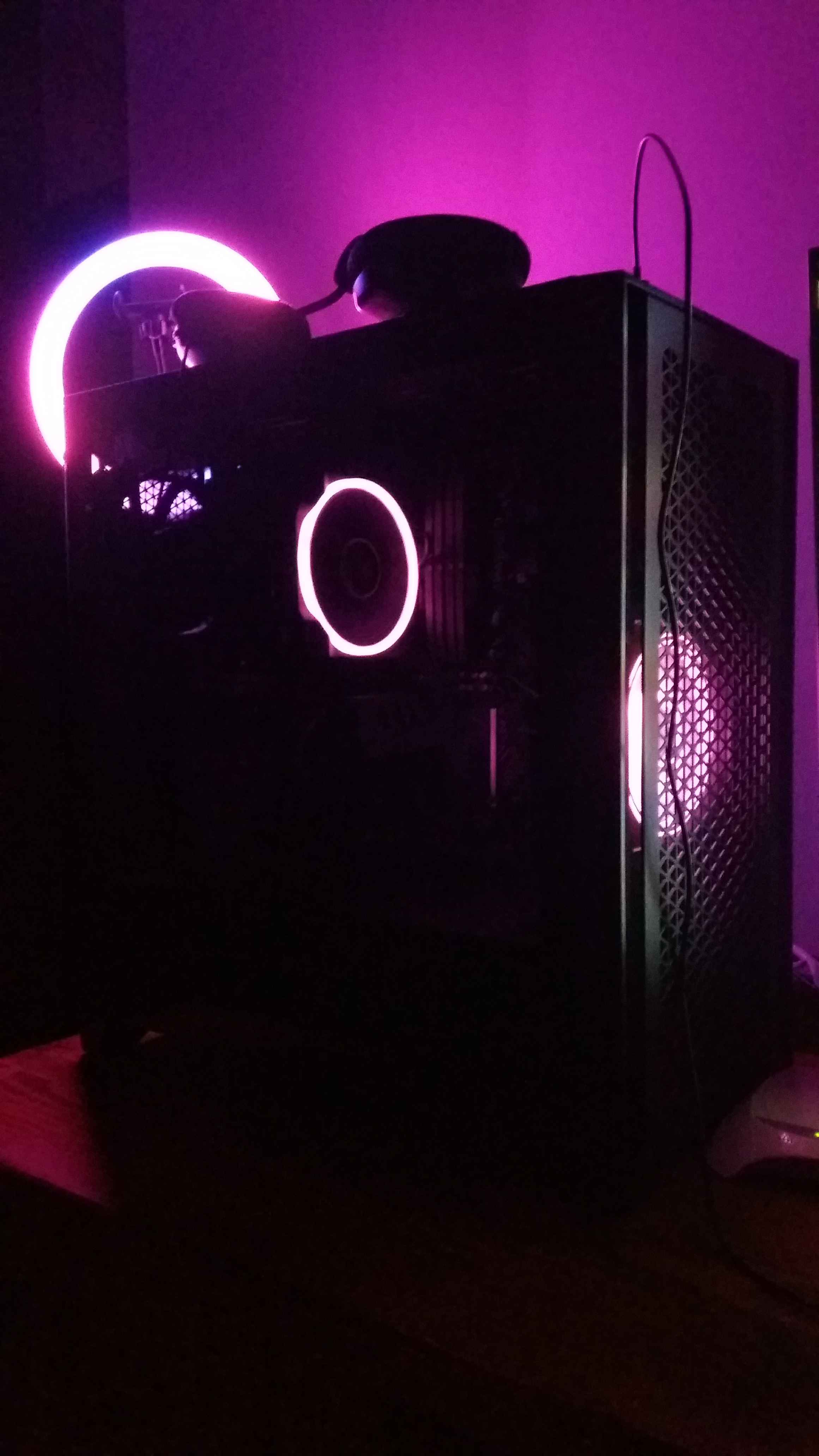 The new main PC actively running. It has a big Corsair computer case with a tempered glass window, and there are two fans lit up in purple.